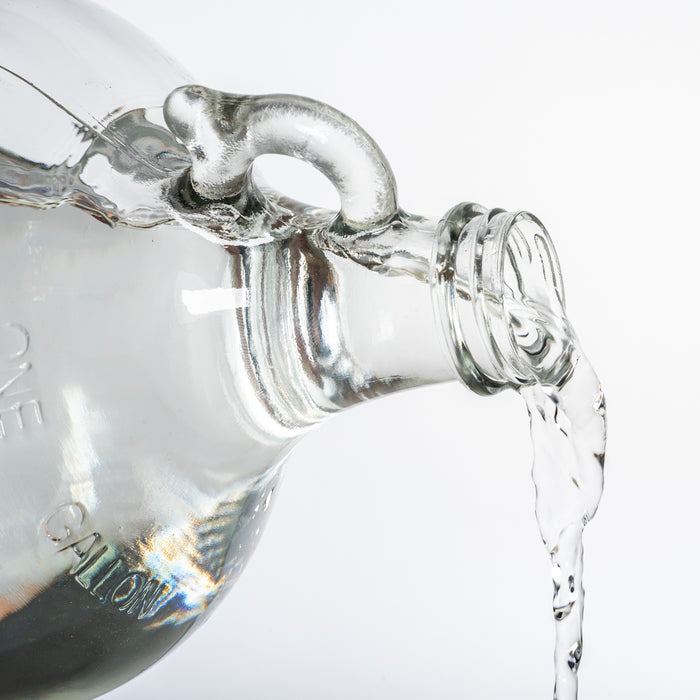 Clear glass container with a spout pouring liquid on a white background